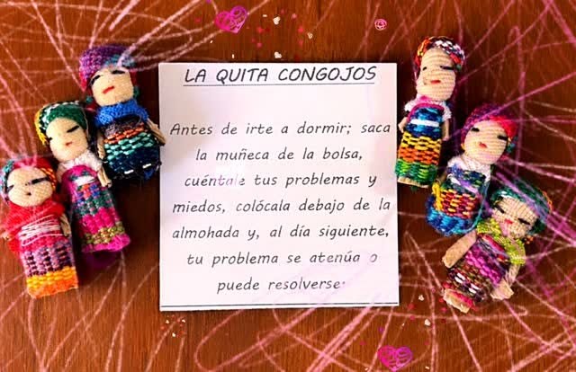 Seis muñequitas vestidas con hilos de colores alrededor de una tarjeta titulada «La quita congojos».
